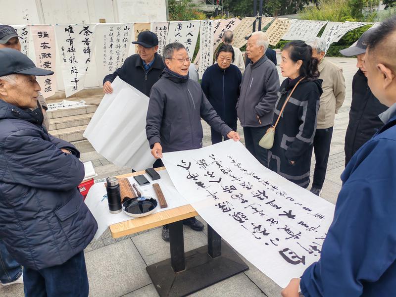 点击图片进入下一页 书画展现场围满了社区老年书画爱好者。